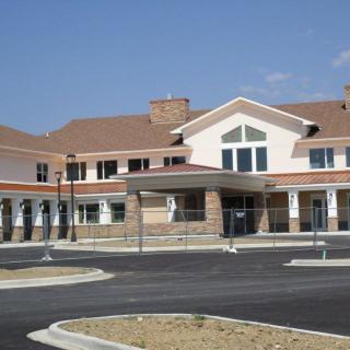 A modern, two-story commercial building with a large entrance and adjacent parking lot.