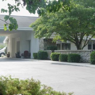 A building entrance surrounded by trees and a driveway.