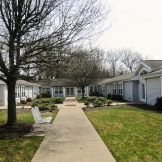 A quiet suburban residential area with a central pathway flanked by houses and trees.