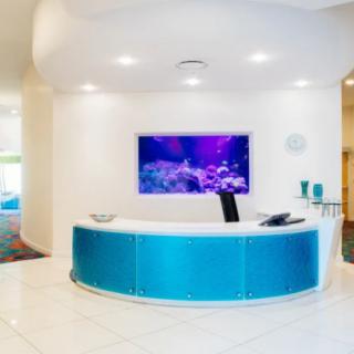 A modern reception area with a blue curved desk and an aquarium display on the wall.