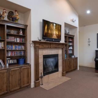 A cozy living room with a fireplace, TV, and bookshelves.