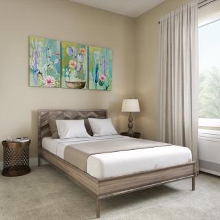 A modern bedroom featuring a neatly made bed, colorful artwork above the headboard, and soft natural lighting from a nearby window.
