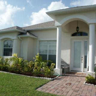 A suburban house with a neatly manicured front yard and a small porch.