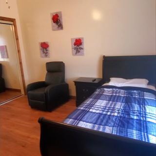 A cozy bedroom featuring a single bed with blue plaid bedding, an armchair, and decorative wall art.