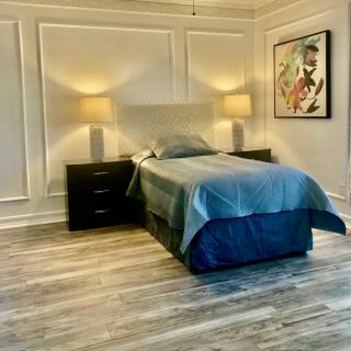 A minimalist bedroom with a single bed, two side lamps, and artwork on the wall.