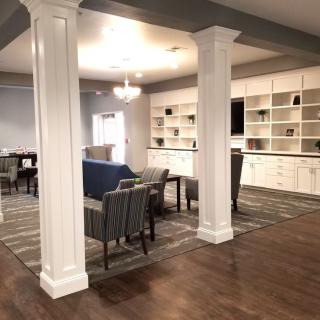 A spacious living area featuring comfortable seating, built-in shelves, and elegant pillars.