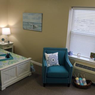 Cozy bedroom with a teal chair and stylish decor.