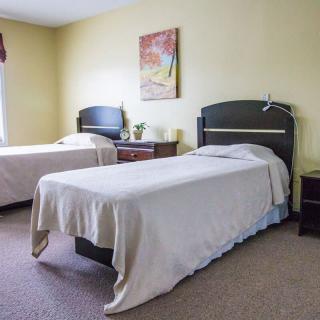 A modestly furnished bedroom with two single beds and a piece of art on the wall.