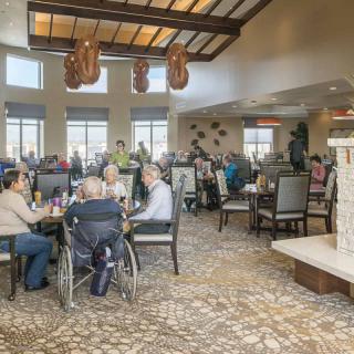 A busy dining area with numerous people enjoying a meal, featuring large windows and a welcoming atmosphere.