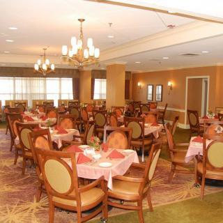 An elegant dining area with neatly arranged tables and chairs, featuring chandeliers and warm lighting.