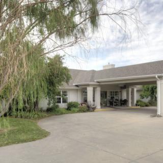 A suburban house with a large driveway and surrounding greenery.
