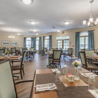 A spacious and elegantly designed dining room with neatly arranged tables and chairs, featuring tasteful decor and soft lighting.