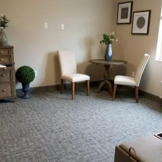 A cozy living room setup with two chairs and a small table, adorned with a vase and decorative elements.
