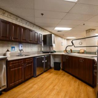 A modern kitchen interior with dark cabinets and wooden flooring.