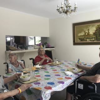 A group of elderly individuals sitting around a dining table, enjoying a meal together.