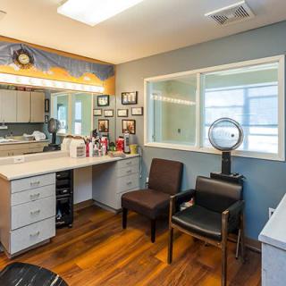 A cozy salon vanity area with a mirror, beauty products, and comfortable seating.