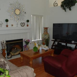 A cozy living room featuring a large television, fireplace, and various decorations.