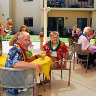 A group of seniors enjoying an outdoor party with drinks and leis.