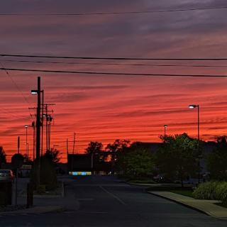 A vibrant sunset casts a warm glow over the urban landscape, painting the sky in shades of orange and purple.