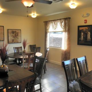 Cozy dining room with multiple tables and chairs, warmly lit by ceiling lights.