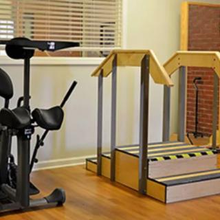 A rehabilitation room equipped with exercise machines and therapy steps.