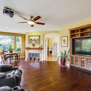 Spacious living room with hardwood floors, ceiling fan, and a cozy fireplace.