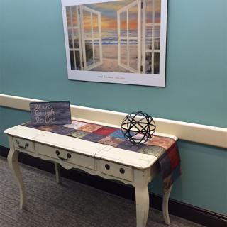 A decorative console table with a colorful runner, featuring a geometric ornament and a framed picture above it.