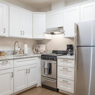 A modern kitchen with white cabinetry and stainless steel appliances.