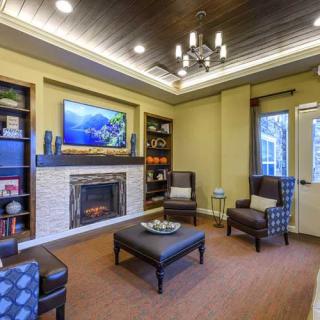 A modern living room with a fireplace, comfortable seating, and a wall-mounted television.