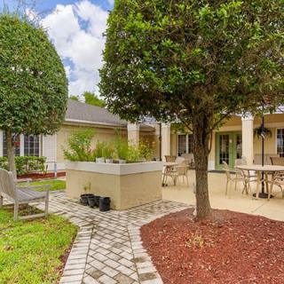 A beautifully landscaped backyard with a patio featuring outdoor seating and a brick pathway.
