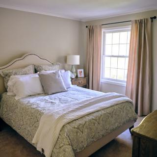 A cozy and well-decorated bedroom featuring a neatly made bed and soft curtains.