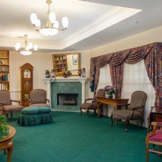 A cozy living room with traditional decor, featuring a fireplace, bookshelves, and comfortable armchairs.