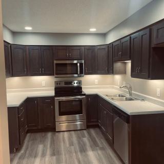 A modern kitchen with dark cabinets and stainless steel appliances.