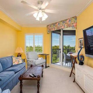 A cozy living room with yellow walls, a blue sofa, and a balcony view.