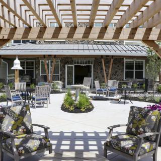 A sunny courtyard with outdoor seating and a pergola overhead.