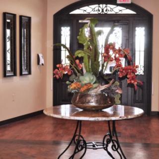 A stylish entryway featuring a round table with an elaborate flower arrangement.
