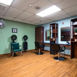 A well-lit hair salon with chairs, mirrors, and hair dryers on a wooden floor.