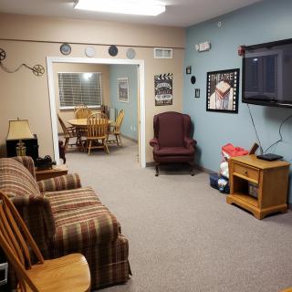 A cozy living room with a television, sofa, and adjoining dining area.