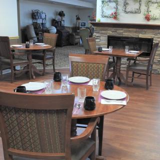 An empty dining area with tables and chairs set for guests.