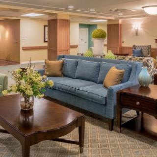 A cozy and inviting lobby area featuring a blue sofa, wooden coffee table, and decorative plants.