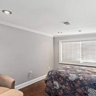 A modern bedroom with minimalist decor featuring a bed, chair, and large window.