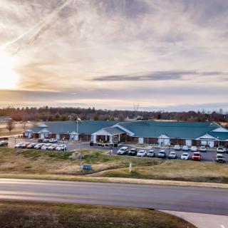 A scenic view of a large building with a parking lot at sunset.