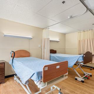 A modern patient room in a hospital featuring two adjustable beds and a clean, organized layout.