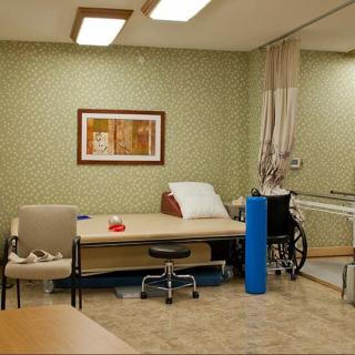 A rehabilitation room equipped with a therapy table, wheelchair, and various medical equipment.