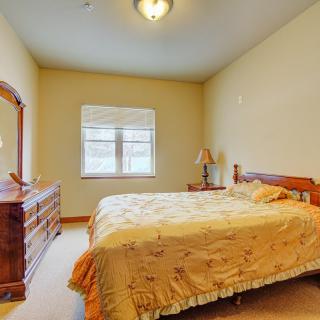A cozy bedroom with a wooden bed and dresser, lit by natural light from the window.