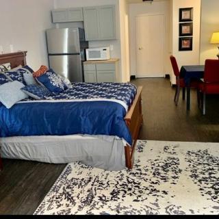 A modern studio apartment with a bed, small kitchen area, and dining table.