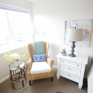 A cozy reading nook with a comfortable armchair, side table, and lamp by a window.