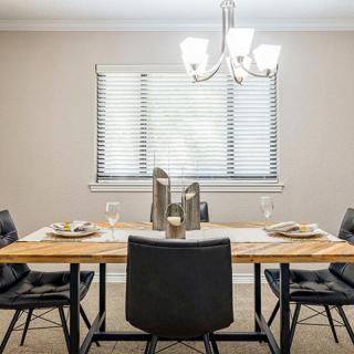 A dining room with a wooden table set for a meal, featuring black chairs and a modern chandelier.