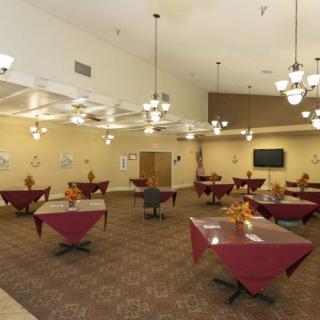 An empty dining hall with neatly arranged tables and overhead chandeliers.