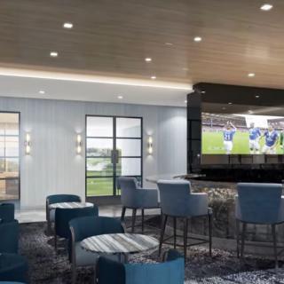 A modern lounge bar with comfortable seating and a large television displaying a sports event.